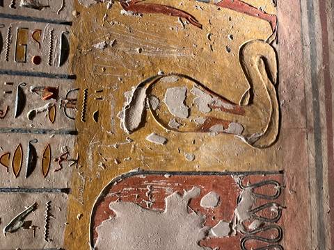Close-up of painted cobra relief with faded pigments on ancient wall