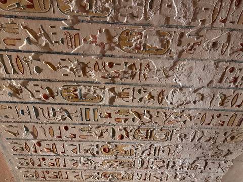Ancient wall showing vertical rows of hieroglyphs with traces of red and yellow paint