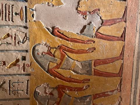 Colorful wall painting depicting ancient Egyptian figures in profile with missing sections