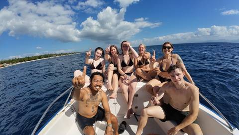 Group of young travellers posing on speedboat in open sea under sunny sky.
