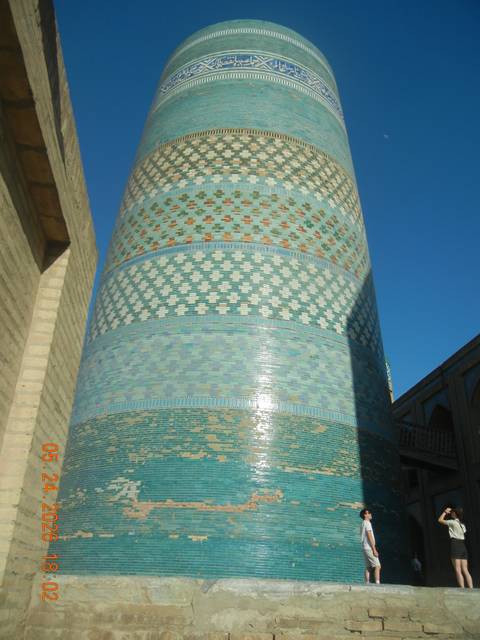 Close-up of turquoise-tiled Kalta Minor minaret glowing in late afternoon light.