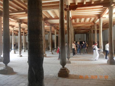 Visitors explore ancient wooden columned hall of Juma Mosque in Khiva.
