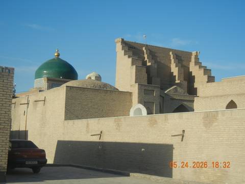 Traditional brick architecture with green dome and stepped walls gleam in afternoon sun.
