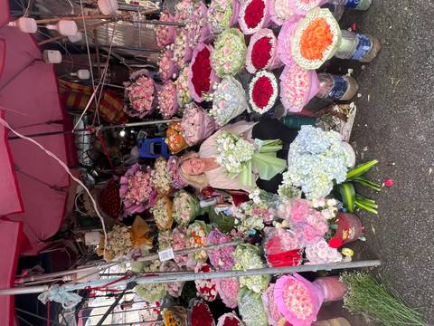 Woman surrounded by colourful bouquets while sitting inside a vibrant flower market stall.