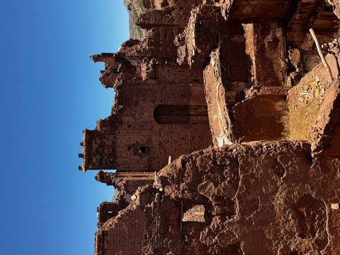 Close-up of weathered red-stone fortress ruins set against a clear blue sky.