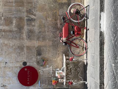 Decorative red bicycle leaned against an old stone wall with charming boutique accents.