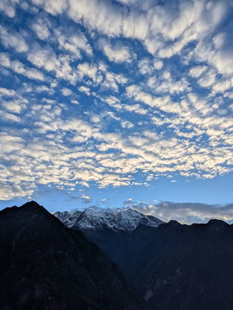 Expansive sky filled with textured white clouds above distant snow-capped Andean peaks.