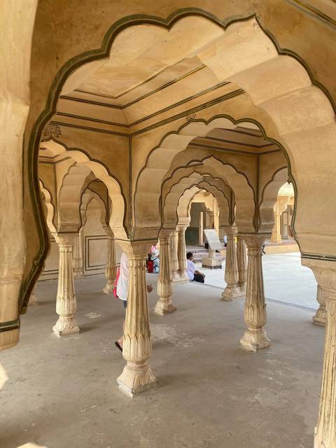 Series of ornate sandstone arches with scalloped edges inside historic fort corridor