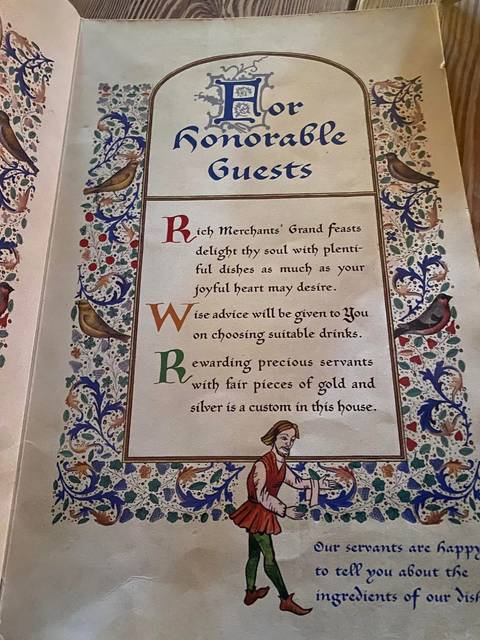 Decorative medieval-style menu page with illuminated letters and floral border.