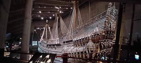 Historic 17th-century wooden warship displayed in a dim museum hall.