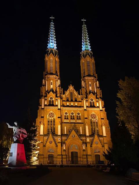 Twin-towered brick church dramatically illuminated against a dark night sky.