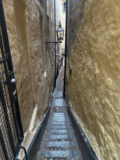 Extremely narrow medieval alley with steep steps between high ochre walls in the old town.