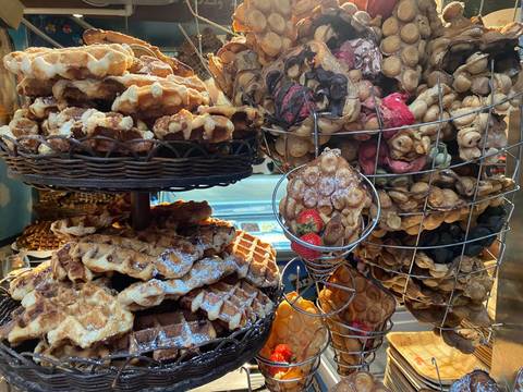 Baskets stacked high with freshly baked waffles and bubble waffles dusted with sugar.