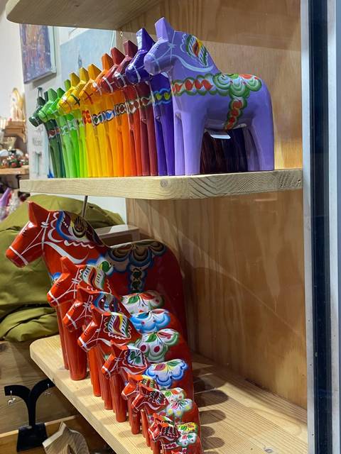 Window display with colorful pillar candles and traditional painted wooden Dala horses.