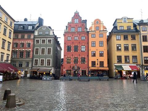 Colorful historic facades surrounding Stortorget square in Stockholm’s Gamla Stan on a wet day.