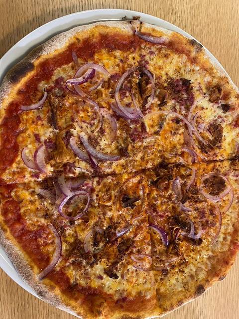 Close-up of a rustic pizza topped with chanterelle mushrooms and red onion slices.