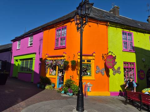 Vibrantly painted shopfronts in the colorful streets of Kinsale under bright sun.
