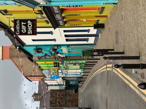 Narrow Irish street lined with bright colorful shopfronts and hanging bunting