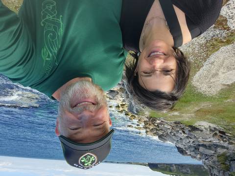 Smiling couple taking a selfie with rocky Atlantic coastline and blue water