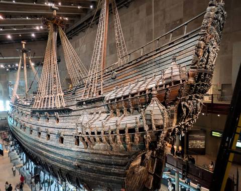 Side view of the preserved 17th-century Vasa warship displayed inside a modern museum hall.