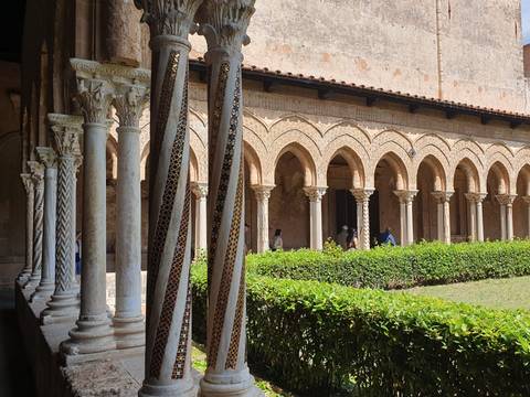 Cloister with elegant marble columns and arches, visitors strolling in the courtyard.