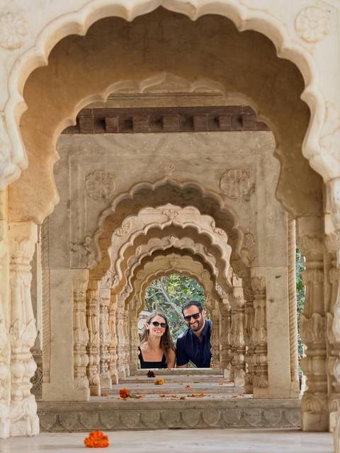 Couple framed by a series of ornate scalloped sandstone arches in Jaipur.