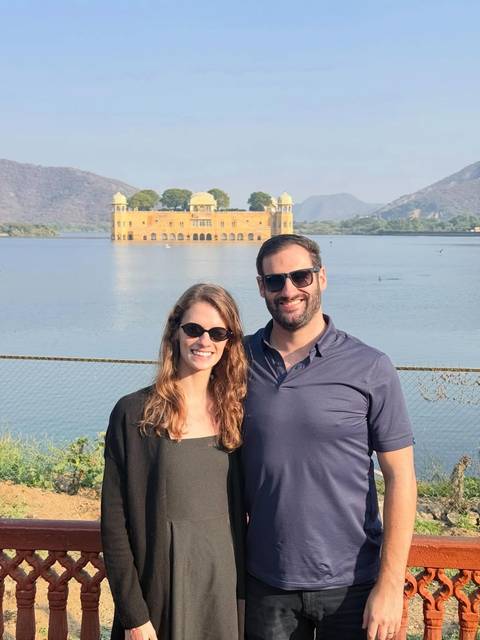 Couple posing beside Jaipur’s lakeside Jal Mahal palace with Aravalli hills in background.
