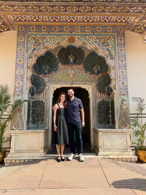 Couple smiling in front of the colorful Peacock Gate at Jaipur City Palace.