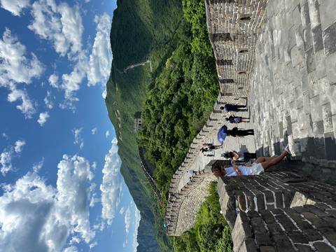 Stone steps and crenellated walls winding over green mountains on the Great Wall of China.