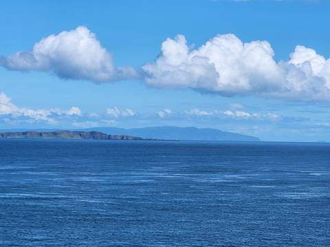 Open Atlantic seascape with distant cliffs under puffy white clouds off the Donegal coast.