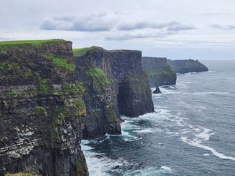 Dramatic view of the Cliffs of Moher plunging into the Atlantic with waves crashing below.