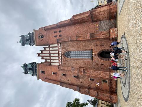Brick twin-tower cathedral soars overhead as visitors enter through the main doorway.