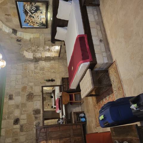 Stone-walled boutique cave hotel room with neatly made bed and rustic furniture.