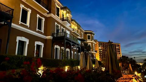 Elegant hotel facade illuminated at dusk with warm lighting against a blue evening sky.