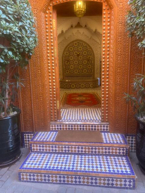 Intricately tiled doorway of a Moroccan riad leading to a richly patterned interior.