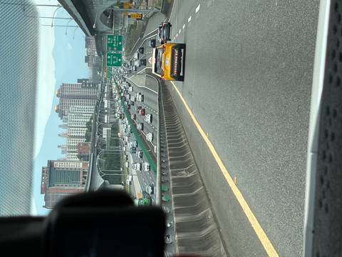 View from a vehicle of busy multilane highway traffic leading toward city high-rises and mountains.