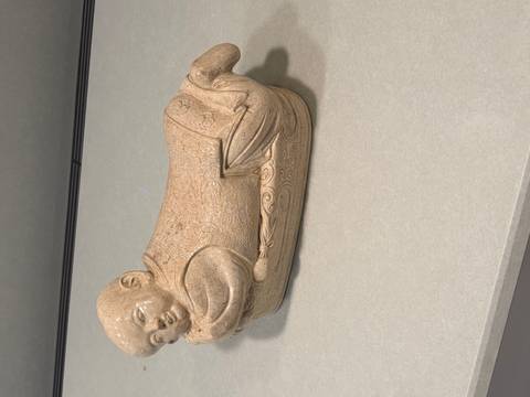 A beige ceramic reclining child figure displayed on a countertop.