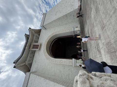Wide shot of the imposing main arch and entrance of the Chiang Kai-shek Memorial Hall with visitors below.