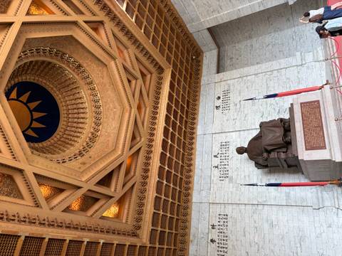 Interior of the Chiang Kai-shek Memorial featuring the seated bronze statue below an ornate coffered ceiling.