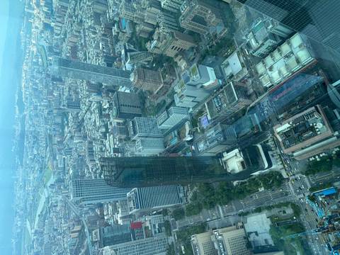 Sweeping aerial view over Taipei’s dense cityscape seen through a blue-tinted observation window.