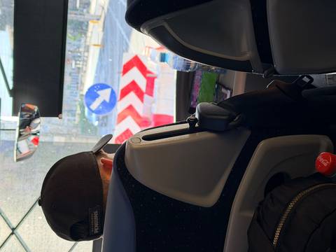 View from a bus seat toward the windshield showing traffic signs and a traveler ahead.