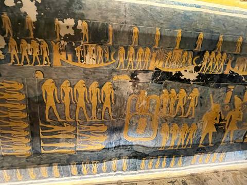 Close-up of colorful pharaonic wall paintings and hieroglyphs inside an ancient tomb chamber.