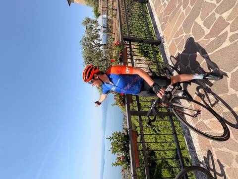 Cyclist pointing over Lake Garda from scenic balcony viewpoint