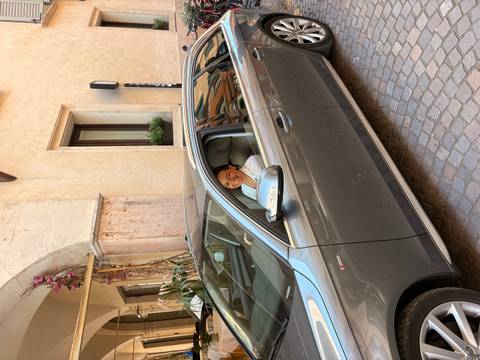 Smiling woman in car driving through narrow cobblestone street