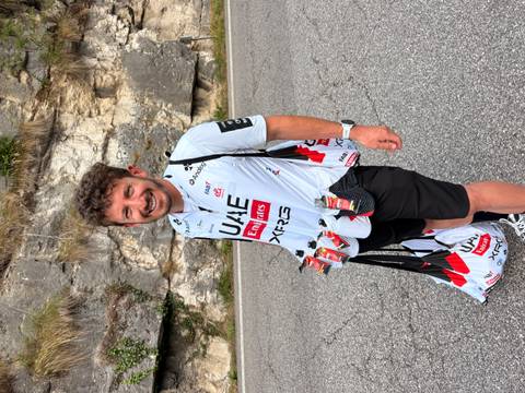 Team support staffer carrying energy gels wearing UAE Emirates cycling kit