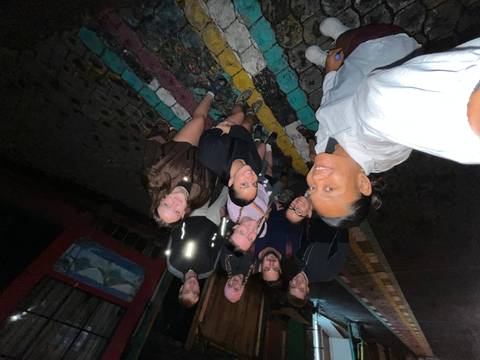 Flash-lit selfie of group standing on colorful tiled street at night