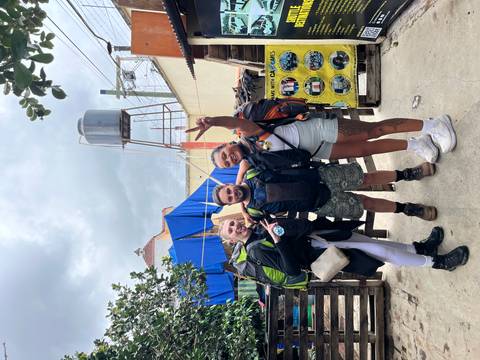 Three backpackers with hiking gear posing cheerfully in urban courtyard