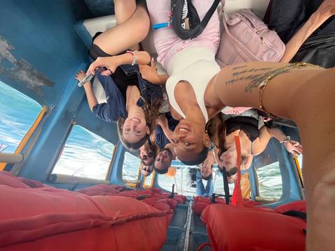 Group selfie inside a small blue boat on clear water