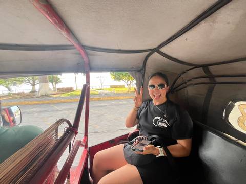Smiling woman flashing peace sign while riding in a tuk-tuk on a city street