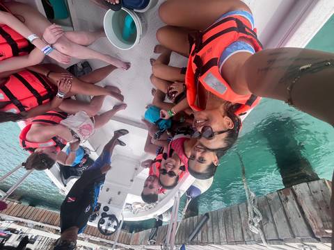 Group in life jackets seated in a small boat on turquoise water preparing for water activity